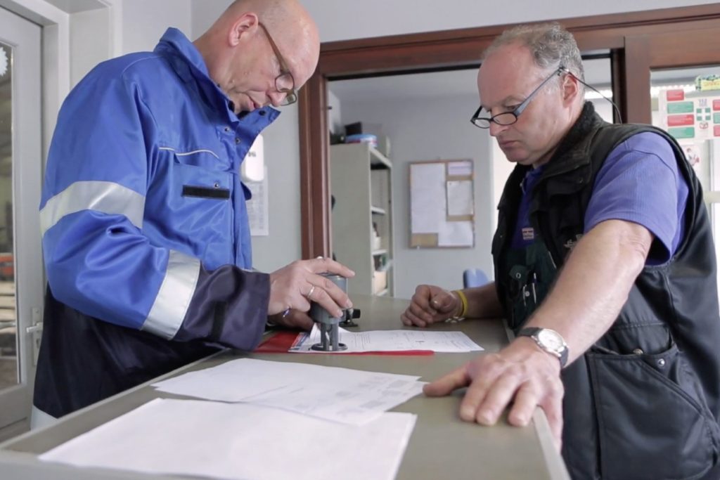 Inspecteur stempelt formulier bij bezoek aan exporteur.